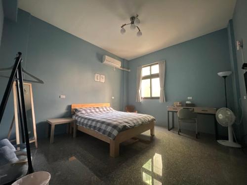 a bedroom with a bed and a desk and a window at Hello Guesthouse in Lugang