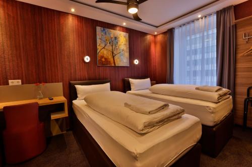 a room with two beds and a desk and a window at Stay-Inn Bielefeld Zentrum in Bielefeld