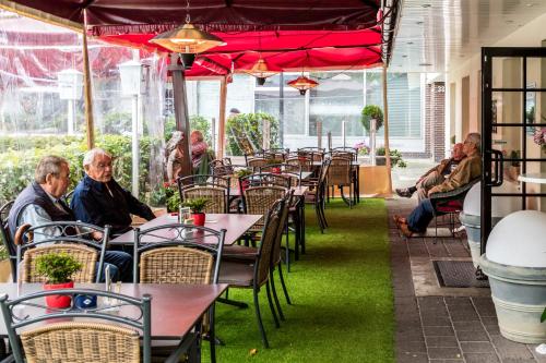 personnes assises à table dans un restaurant avec des parasols rouges dans l'établissement Hotel Gambrinus Arnsberg, à Arnsberg