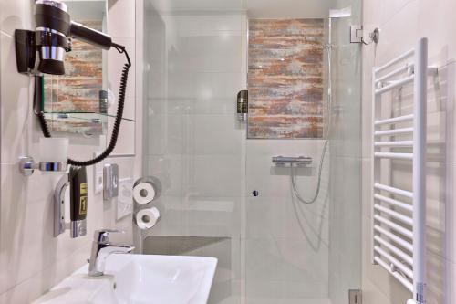 a white bathroom with a shower and a sink at Stay-Inn Bielefeld Zentrum in Bielefeld