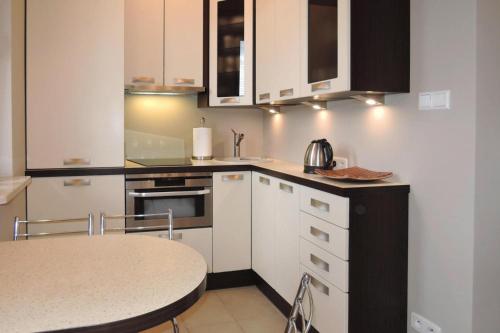 a kitchen with white cabinets and a table in it at Holiday flat, Swinoujscie in Świnoujście