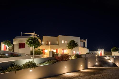 a large white house with lights in the night at Potnia Theron Suites in Akrotiri