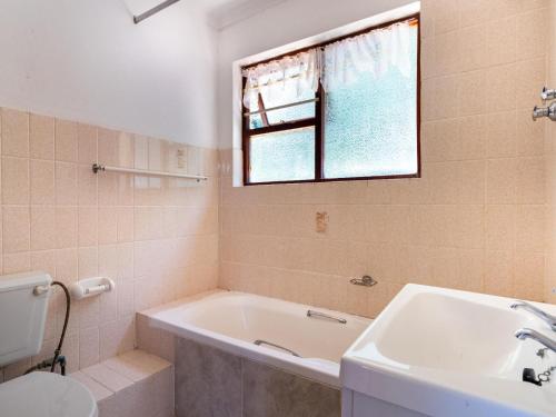 baño con bañera, lavabo y ventana en The Thatches, en Kei-mouth Village
