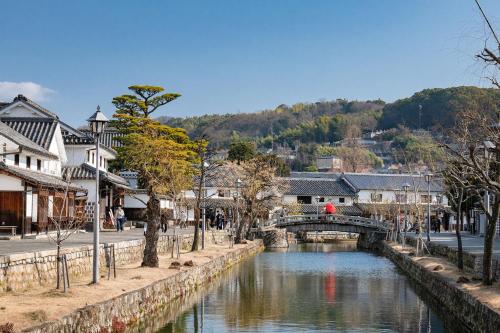 a river in a town with a bridge and buildings at The OneFive Garden Kurashiki in Kurashiki
