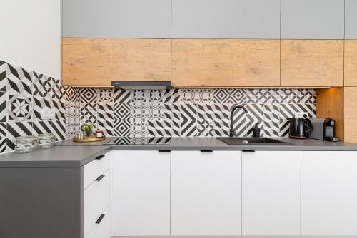 a kitchen with white cabinets and a black and white patterned wall at Studio Cracow Wawrzyńca by Renters in Krakow