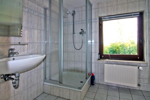a bathroom with a shower and a sink and a window at Holiday home on the dike, Büsum in Westerdeichstrich