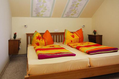 Duas camas num quarto com almofadas cor-de-laranja e amarela em Apartment house Nicole, Zinnowitz em Zinnowitz