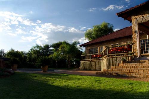 a house with a grass yard next to a building at Boubou Bed and Breakfast in Rustenburg