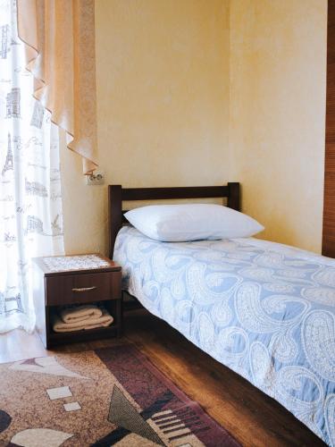 a bedroom with a bed and a nightstand next to a window at Filvarok Hotel in Brody