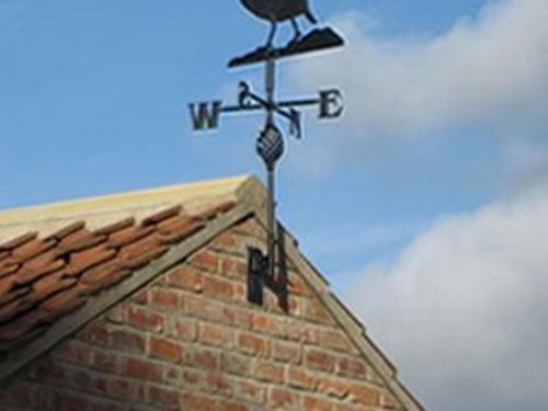 a bird on top of a building with a weather vane at Brickfields Farm in Kirkbymoorside
