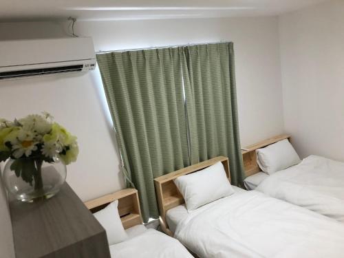 a room with two beds and a vase of flowers on a table at Kumamoto - House / Vacation STAY 75194 in Kumamoto