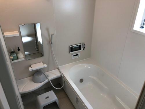 Baño blanco con bañera y lavamanos en Kumamoto - House / Vacation STAY 75194, en Kumamoto