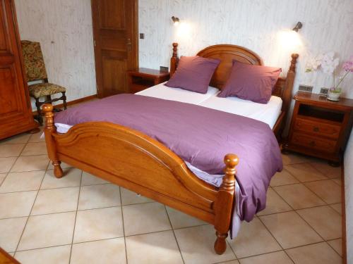 Un dormitorio con una gran cama de madera con almohadas moradas en Appartement de 3 chambres avec wifi a Epfig, en Epfig