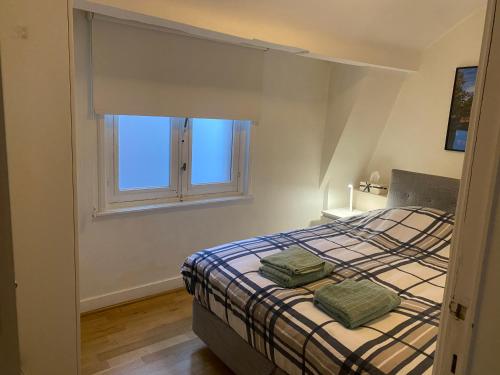 a bedroom with a bed with two green towels on it at Cosy little house in Bruges