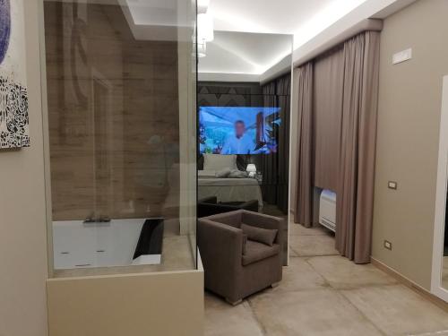 uma sala de estar com uma cadeira e uma televisão em Hotel Parco delle Querce em Crispiano