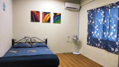 a bedroom with a bed and two paintings on the wall at Hornbill Homestay Samarahan in Kota Samarahan