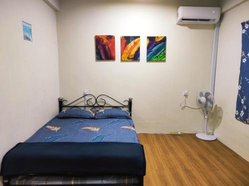 a bed in a room with paintings on the wall at Hornbill Homestay Samarahan in Kota Samarahan