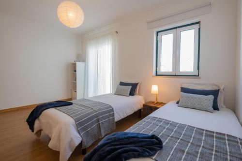 a bedroom with two beds and a window at MilDreams House in Vila Nova de Milfontes