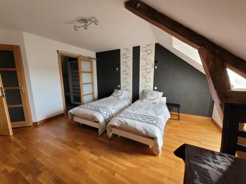 two beds in a room with wooden floors at Le Pont Sée in Romille