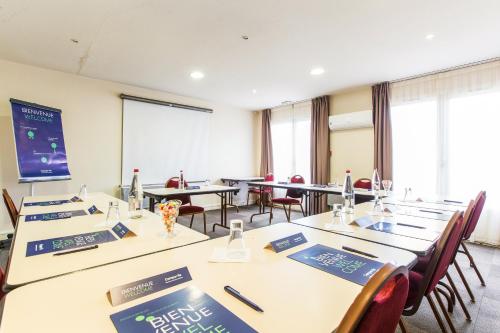 une salle de conférence avec des tables, des chaises et un écran dans l'établissement Campanile Château-Thierry, à Château-Thierry