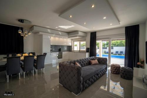 a large living room with a couch and a kitchen at Villas Sabun - modern house with heated pool in Privlaka