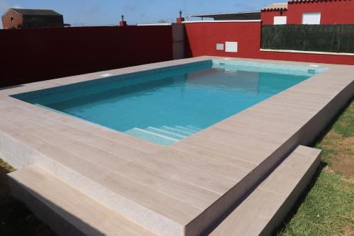 een groot zwembad met een houten terras in een achtertuin bij Chalet Brisa Veraniega in Conil de la Frontera