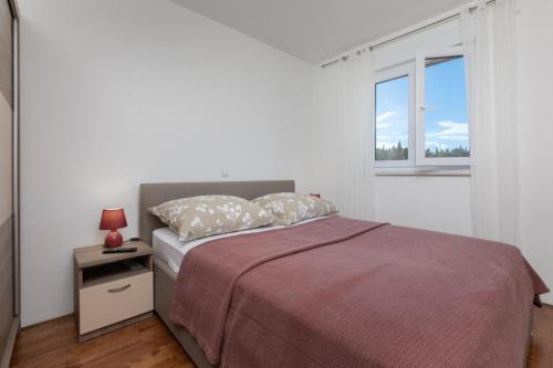 a white bedroom with a bed and a window at Sea View Apartment Michelle near Osejava in Makarska