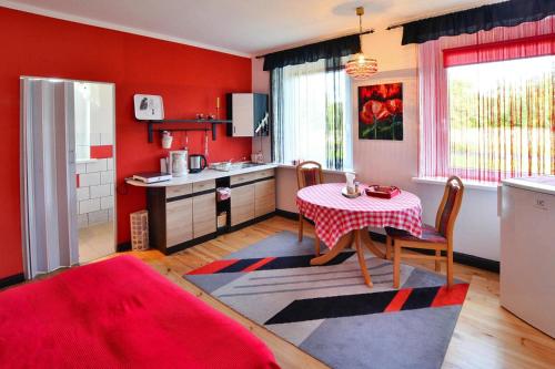 a kitchen with a table and a red wall at Comfortable 2 person holiday apartment in the countryside Drezno in Stare Wierzchowo