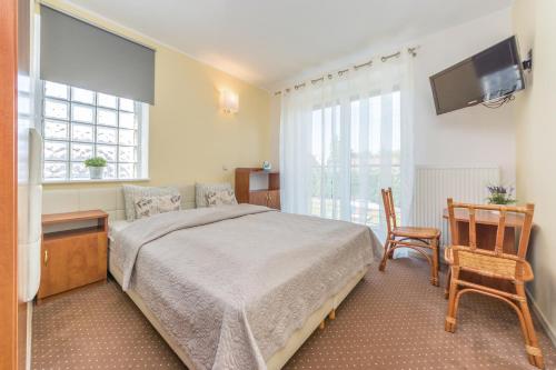 a bedroom with a bed and a tv and a chair at Aparthotel Luna&Sol in Jastrzębia Góra