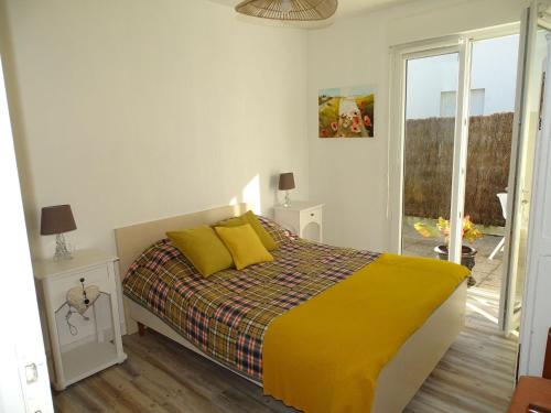 um quarto com uma cama com lençóis amarelos e uma janela em Comfortable holiday home between Cote Sauvage and sandy beaches em Saint-Pierre-Quiberon