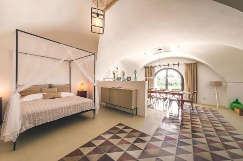 1 dormitorio con cama con dosel y comedor en HelloAPULIA - Panoramic Masseria Minetta with private pool, en Cisternino