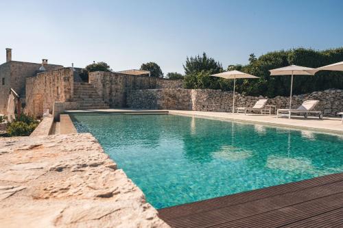 einen Pool mit 2 Stühlen und Sonnenschirmen in der Unterkunft HelloAPULIA - Masseria Minetta - Infinity Saltwater Pool & Scenic View in Cisternino