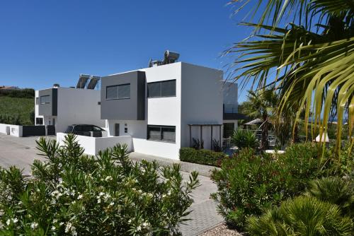 a white house with palm trees in front of it at Exclusieve Villa met zeezicht en privézwembad in Atalaia in Lourinhã