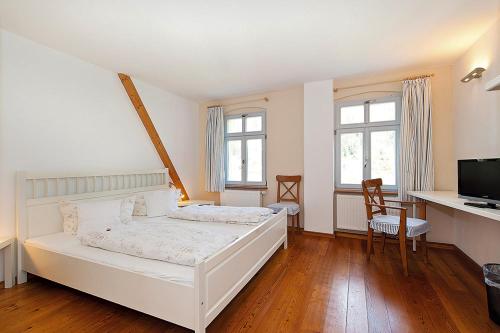 1 Schlafzimmer mit einem weißen Bett, einem Schreibtisch und 2 Fenstern in der Unterkunft Landgasthaus Ziegelscheune in Krippen