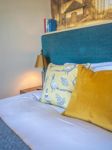 a bed with a blue headboard and two pillows at Harper's Steakhouse with Rooms, Haslemere in Haslemere
