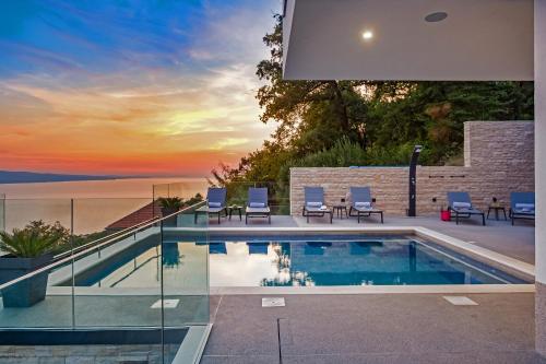 a swimming pool in a house with a sunset at Villa Dispet, sea view, pool, jacuzzi, sauna, cinema in Omiš
