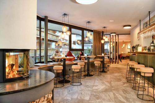 un restaurante con chimenea y un bar con mesas en Residence Panorama, en Pfelders
