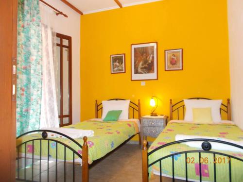 two beds in a room with yellow walls at Horizon Blue, Kalamitsi, Lefkas in Kalamitsi