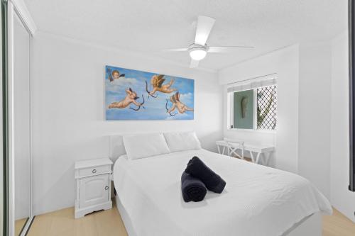 a white bedroom with a white bed and a painting at The Penthouse Mooloolaba, Private Luxury Rooftop Living in Mooloolaba