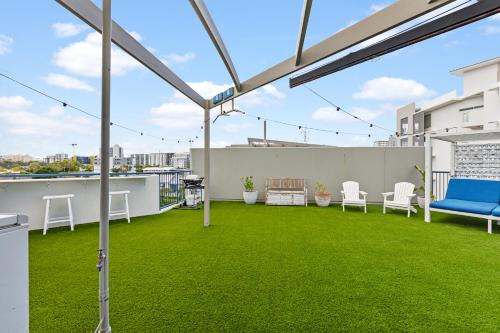 a rooftop patio with green grass and white chairs at The Penthouse Mooloolaba, Private Luxury Rooftop Living in Mooloolaba