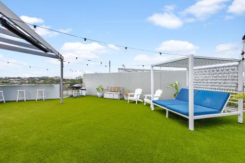 a patio with blue chairs on a green lawn at The Penthouse Mooloolaba, Private Luxury Rooftop Living in Mooloolaba