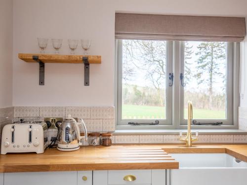 cocina con fregadero y 2 ventanas en Chestnut Cottage, en Winchcombe
