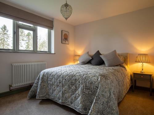 a bedroom with a bed and two windows at Chestnut Cottage in Winchcombe