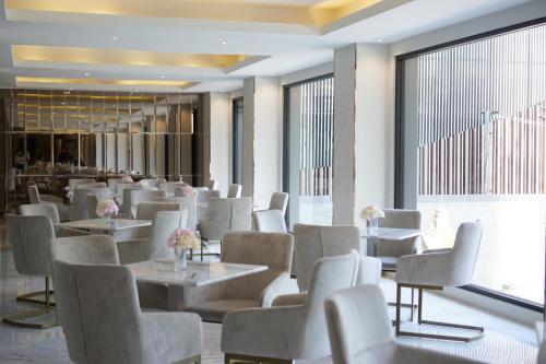 ein Restaurant mit weißen Stühlen und Tischen und Fenstern in der Unterkunft Hermann Hotel Pattaya in Pattaya