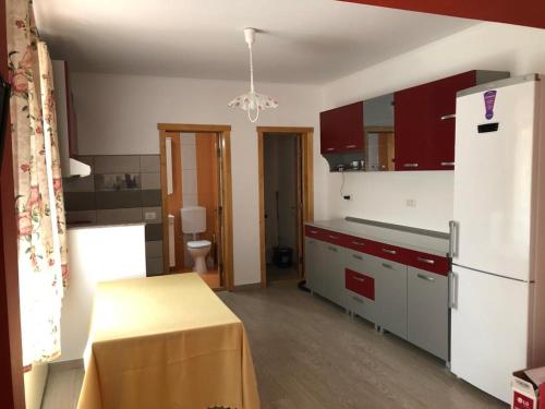 a kitchen with red cabinets and a white refrigerator at Casuta Lavi Constanta in Constanţa