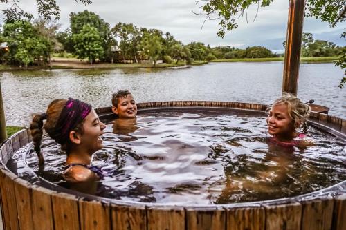 a group of people in a jacuzzi in a wooden bath tub at AfriCamps Hoedspruit in Hoedspruit