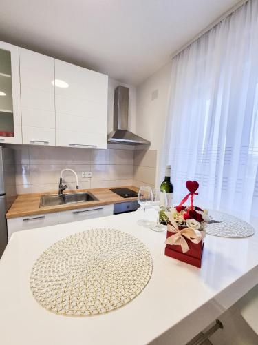 a kitchen with white cabinets and a table with a wine glass at Apartment Ane 2 in Tisno
