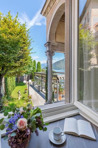 an open window with a vase of flowers and a book at Villa Maria Boutique Hotel in Cannobio