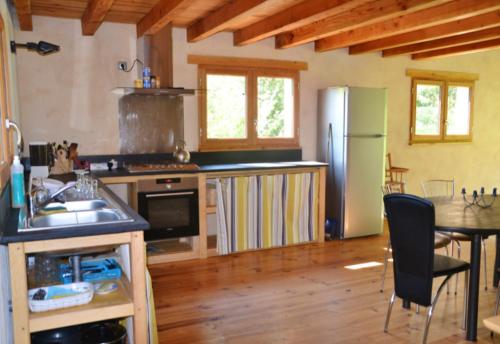 cocina con nevera y mesa con sillas en Maison de 2 chambres avec piscine partagee jardin clos et wifi a Gembrie, en Gembrie