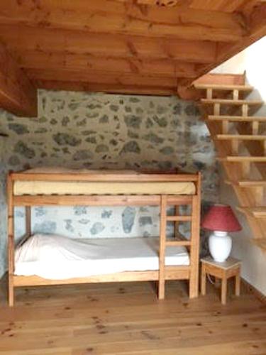 Ce lit superposé en bois se trouve dans un dortoir doté d'un escalier. dans l'établissement Maison accueillante à Gembrie avec piscine partagée, à Gembrie